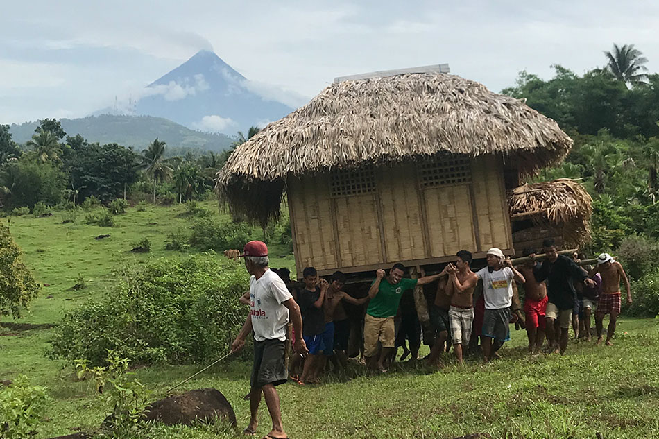 Local community carrying a small house to a safe location